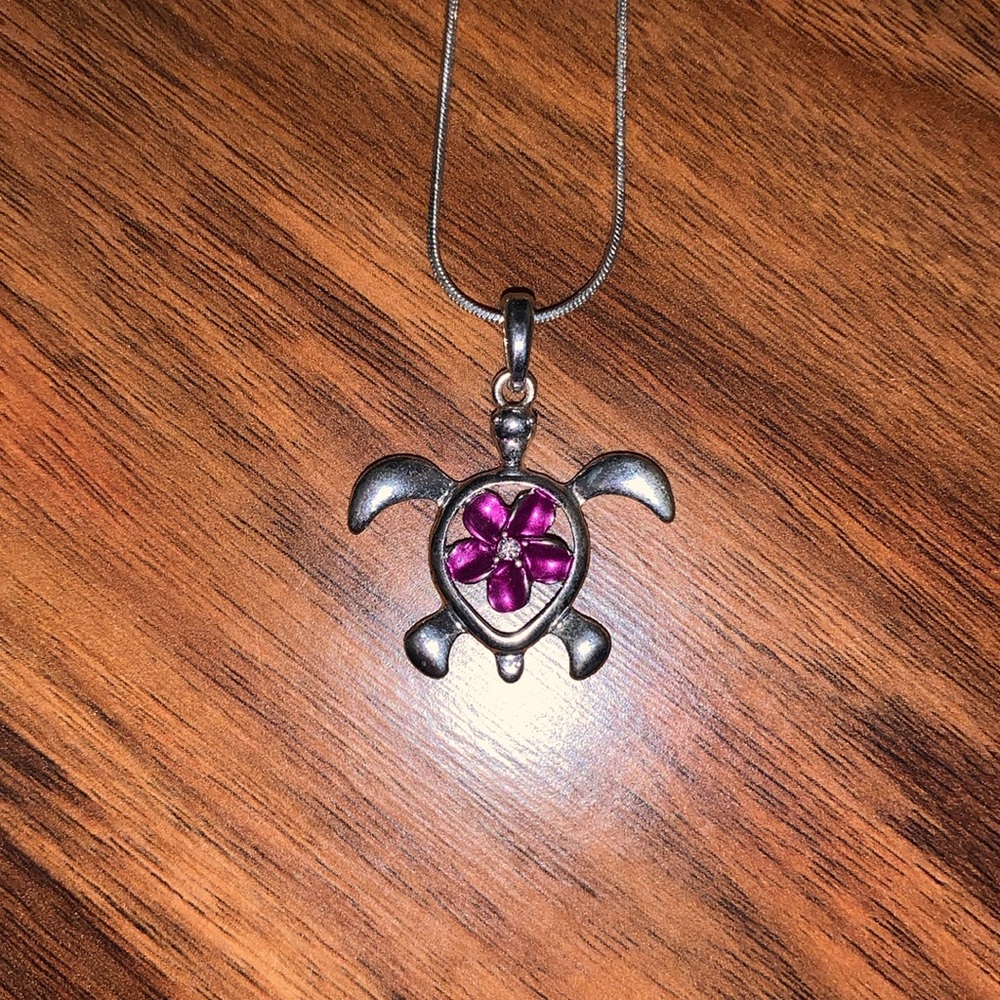 Sea turtle necklace with purple flower in the center. On silver 18” inch chain